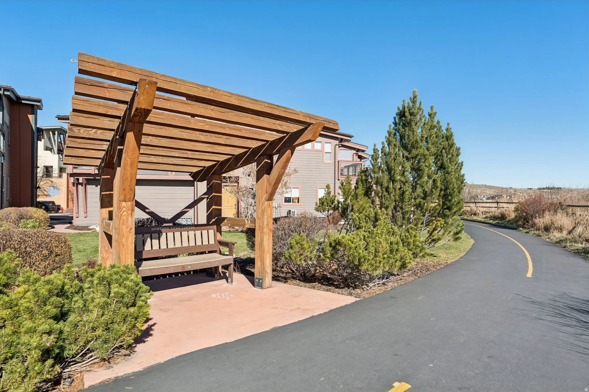 Wood pergola structure with an integrated bench, set on a paver patio
