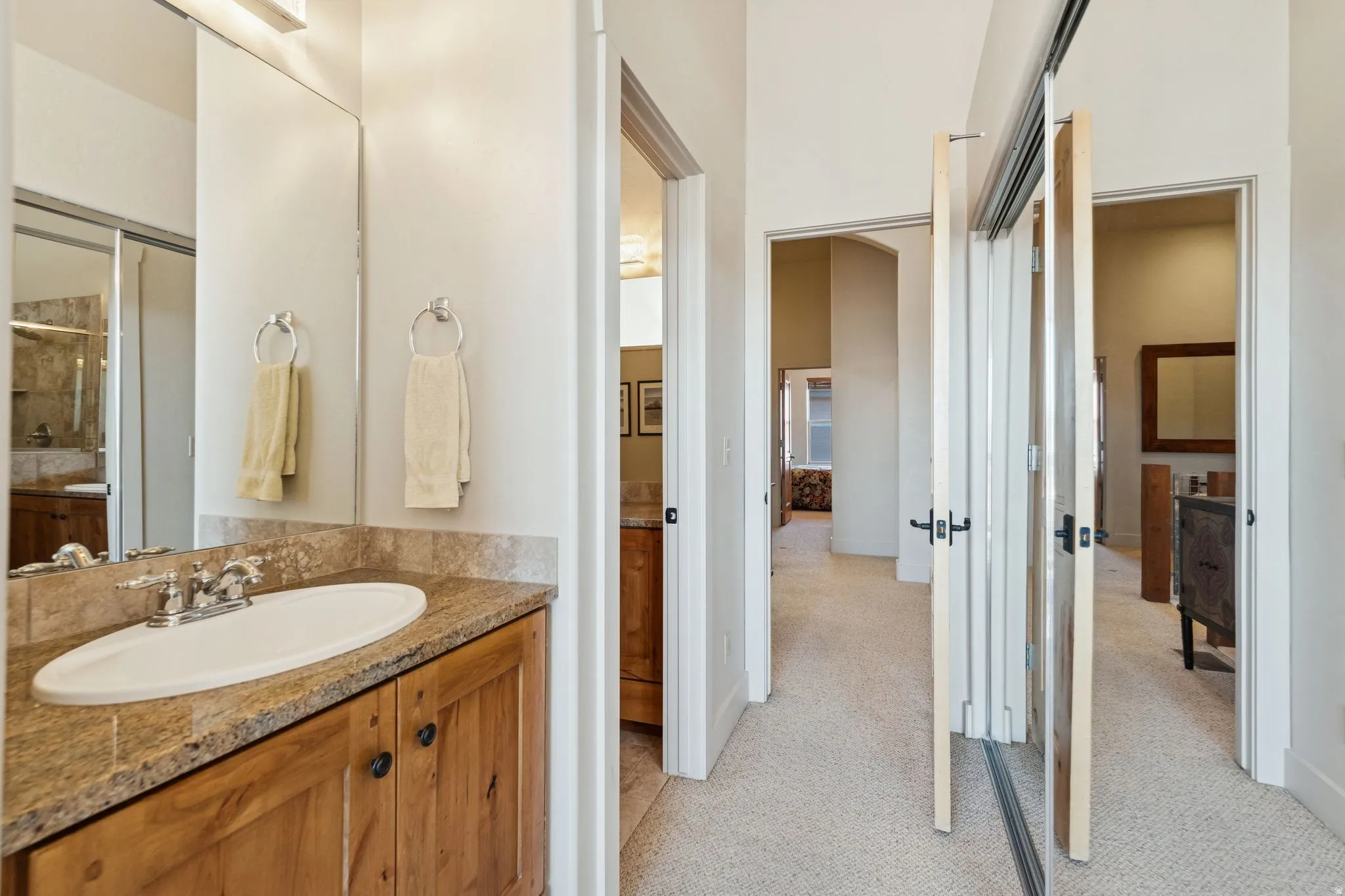 Bathroom vanity featuring a granite countertop, undermount sink, and wood-finish cabinetry