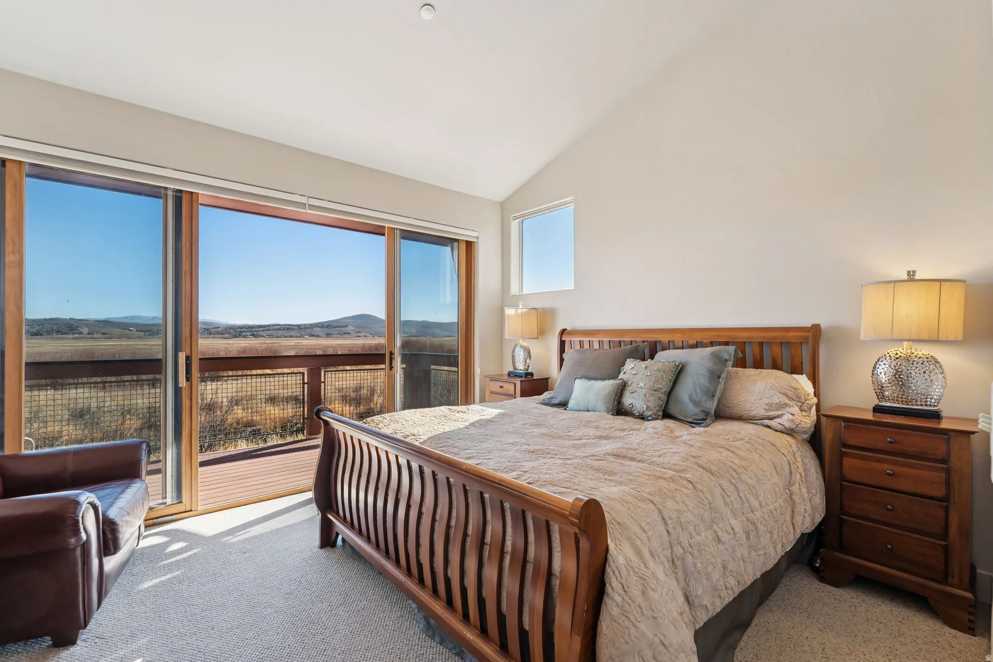 Bedroom featuring vaulted ceilings, a built-in window, and a full-light glass sliding door opening to an outdoor deck