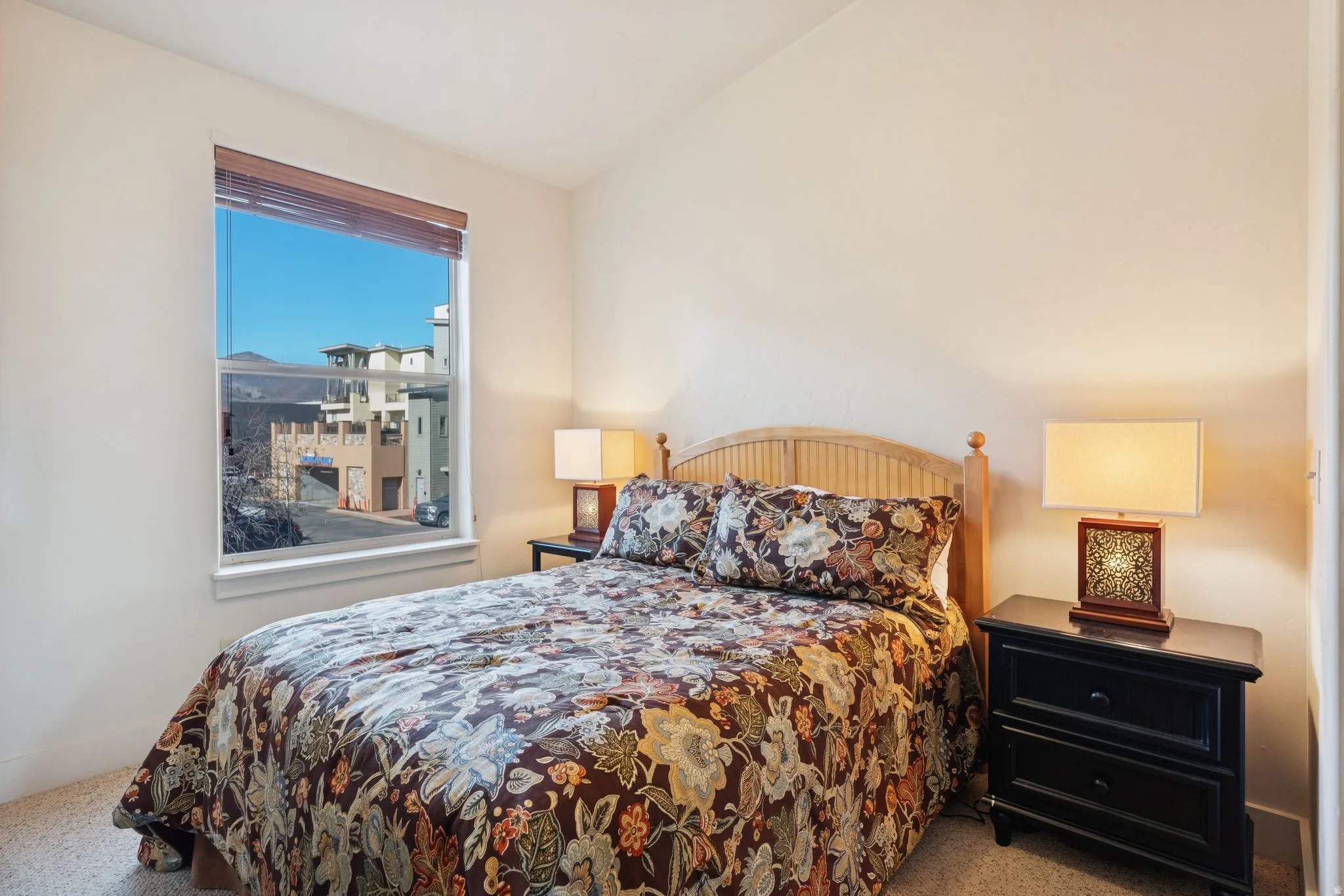Bedroom featuring a large window with wooden blinds, a light-toned wood headboard, and neutral wall paint