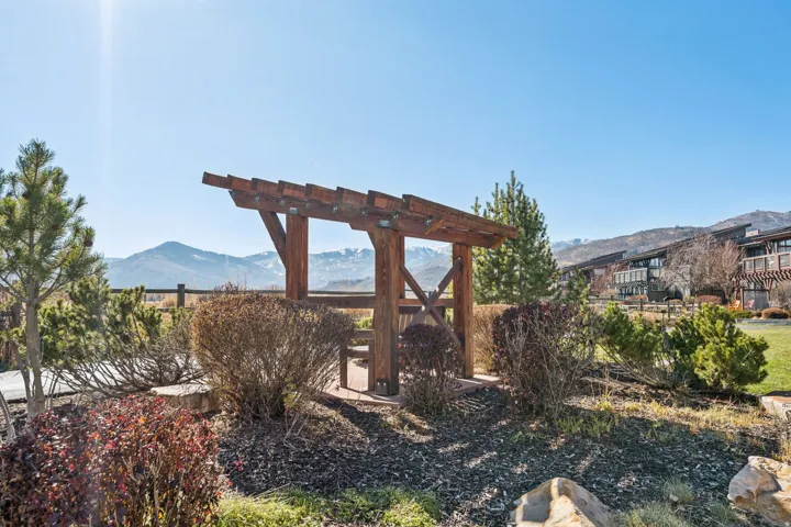 Wood pergola structure with mountain backdrop, surrounded by established landscaping