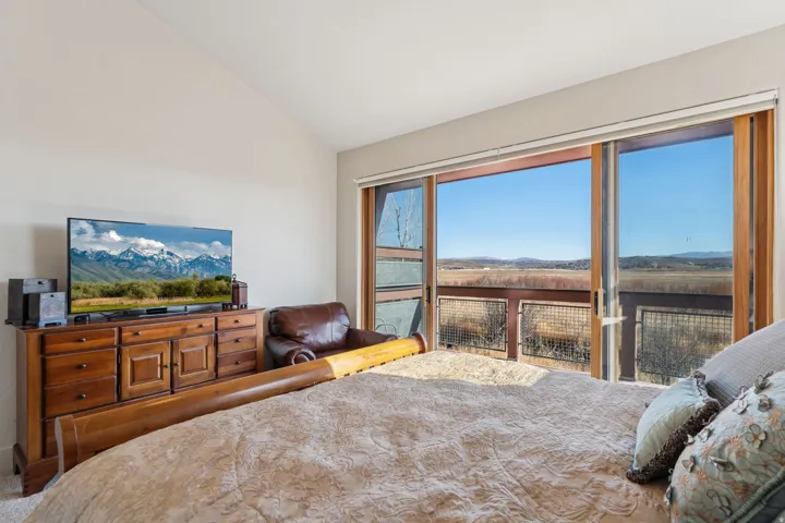Vaulted ceiling bedroom featuring expansive sliding glass doors opening to a private balcony