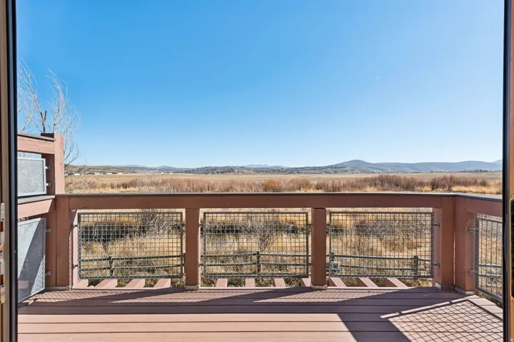 Outdoor deck featuring composite decking, wood railing with metal grid inserts, and expansive natural landscape