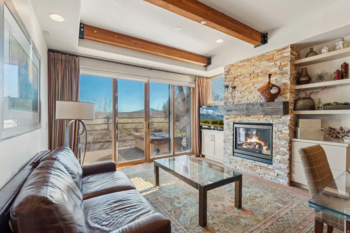 Living area featuring a floor-to-ceiling stone-faced fireplace with a substantial timber mantel