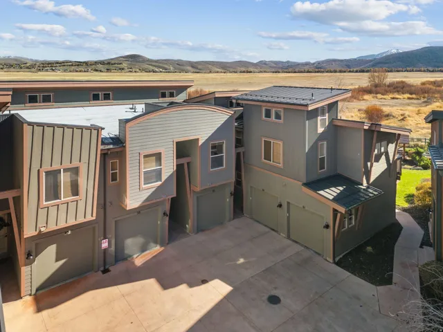 Contemporary multi-level townhome exteriors featuring varied siding textures, private garages, and a paved drive