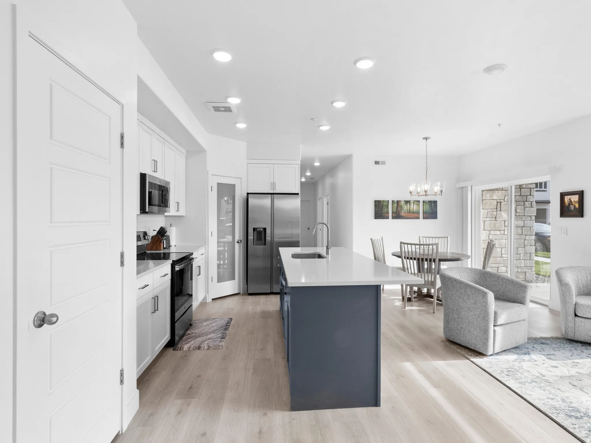 Dual tone kitchen with dual tone cabinetry, a center island with sink, stainless steel appliances, open floor plan, and light wood-type flooring