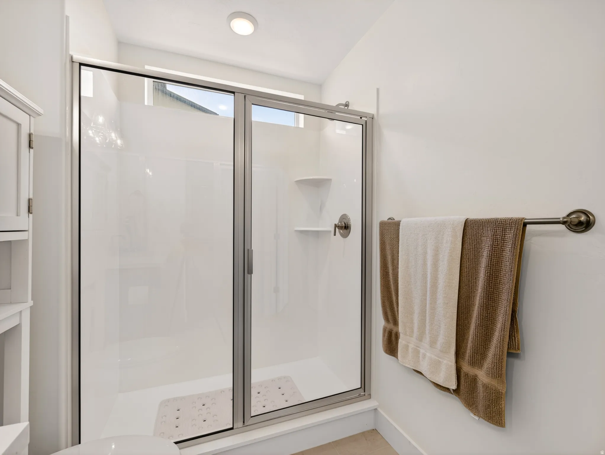 Glass-enclosed shower with sliding door and built-in shelving