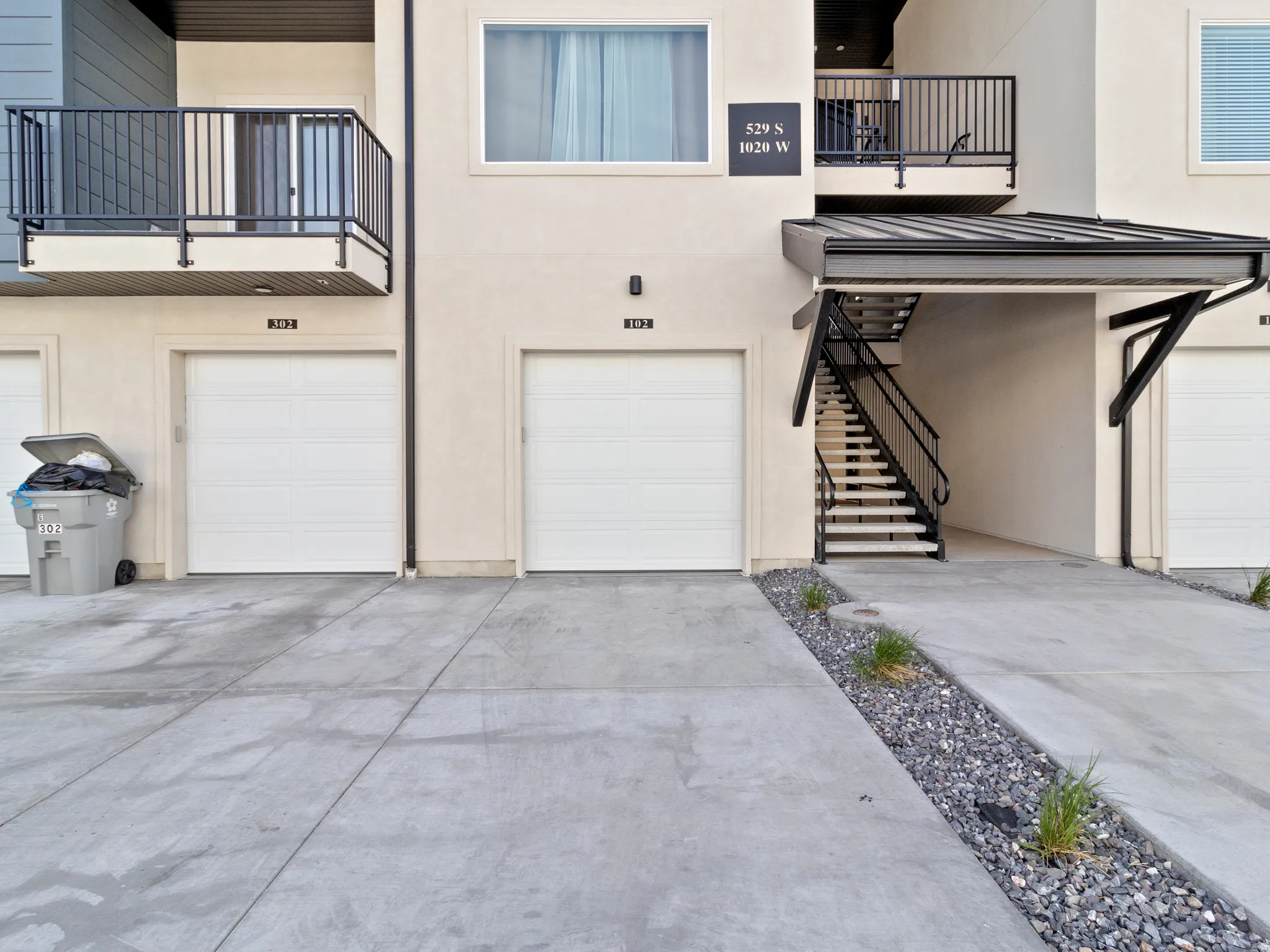Entrance to property featuring a standing seam roof, an attached garage, stucco siding, and driveway