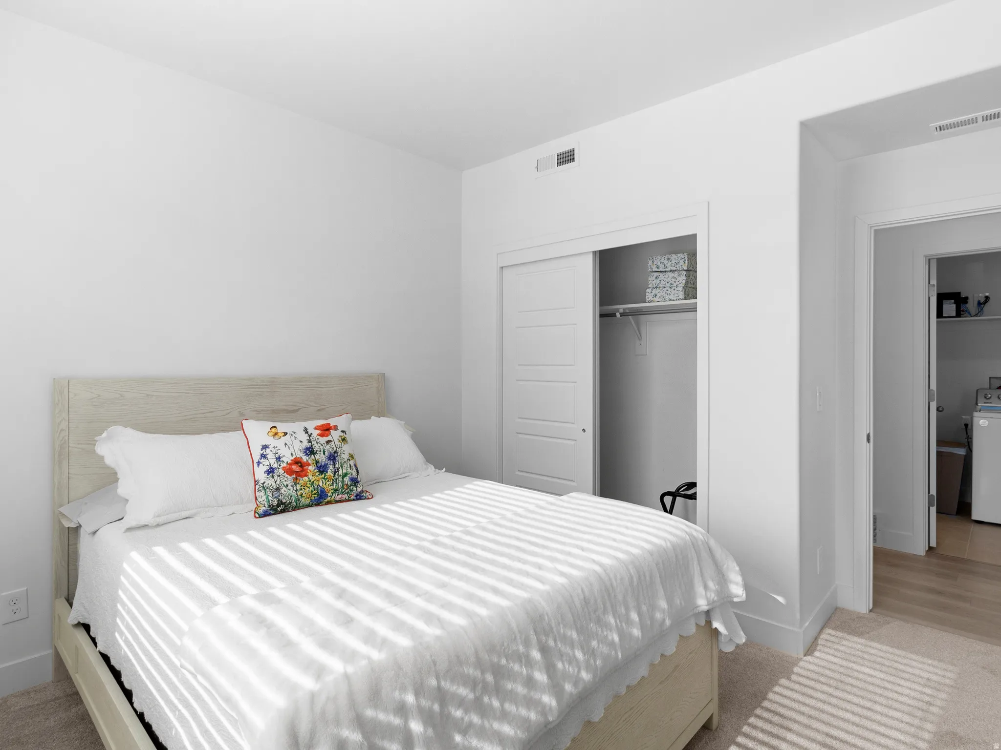 Bedroom with a closet, light carpet, and washer / dryer