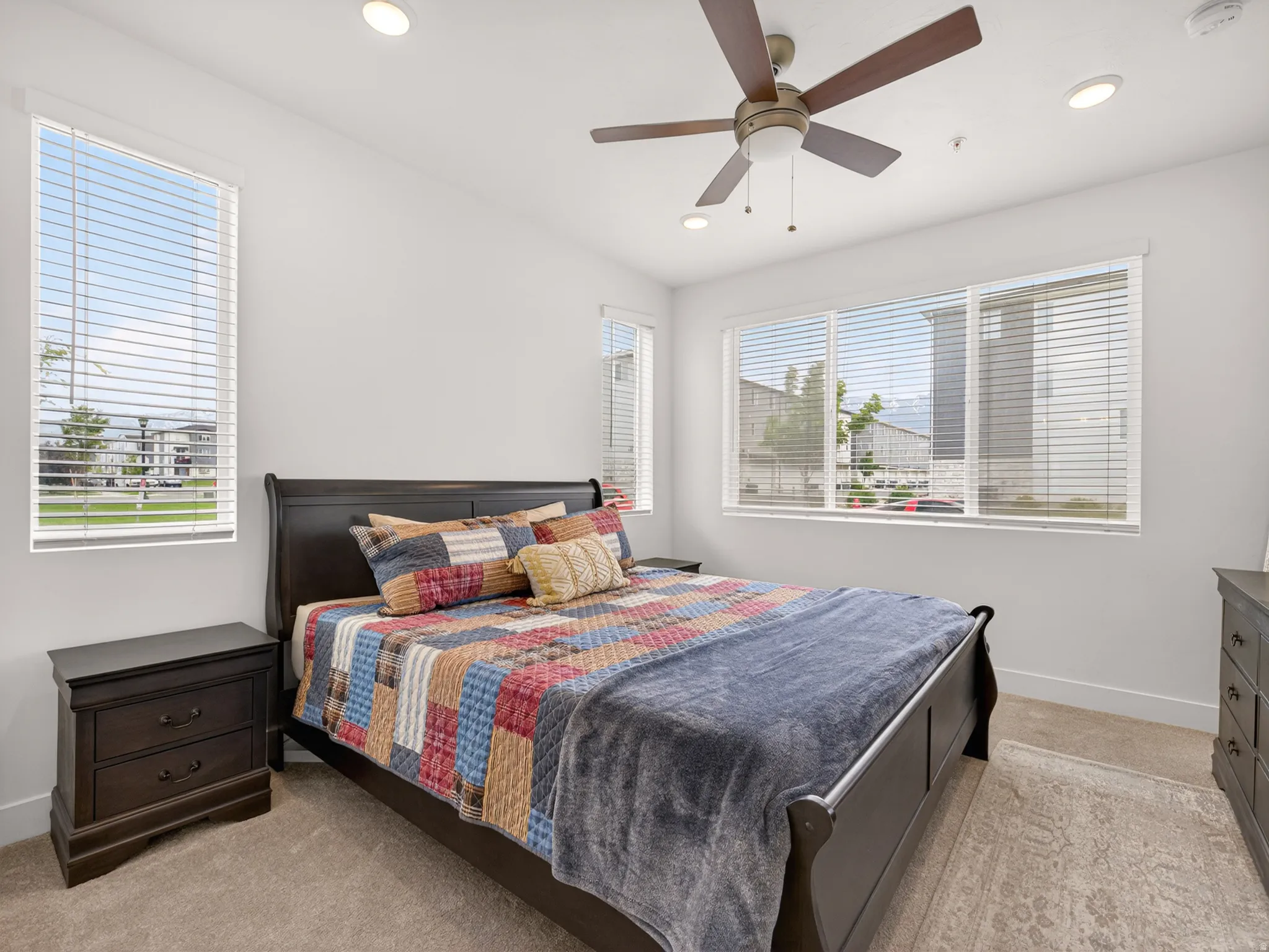 Carpeted bedroom with a ceiling fan, recessed lighting, and multiple windows with blinds
