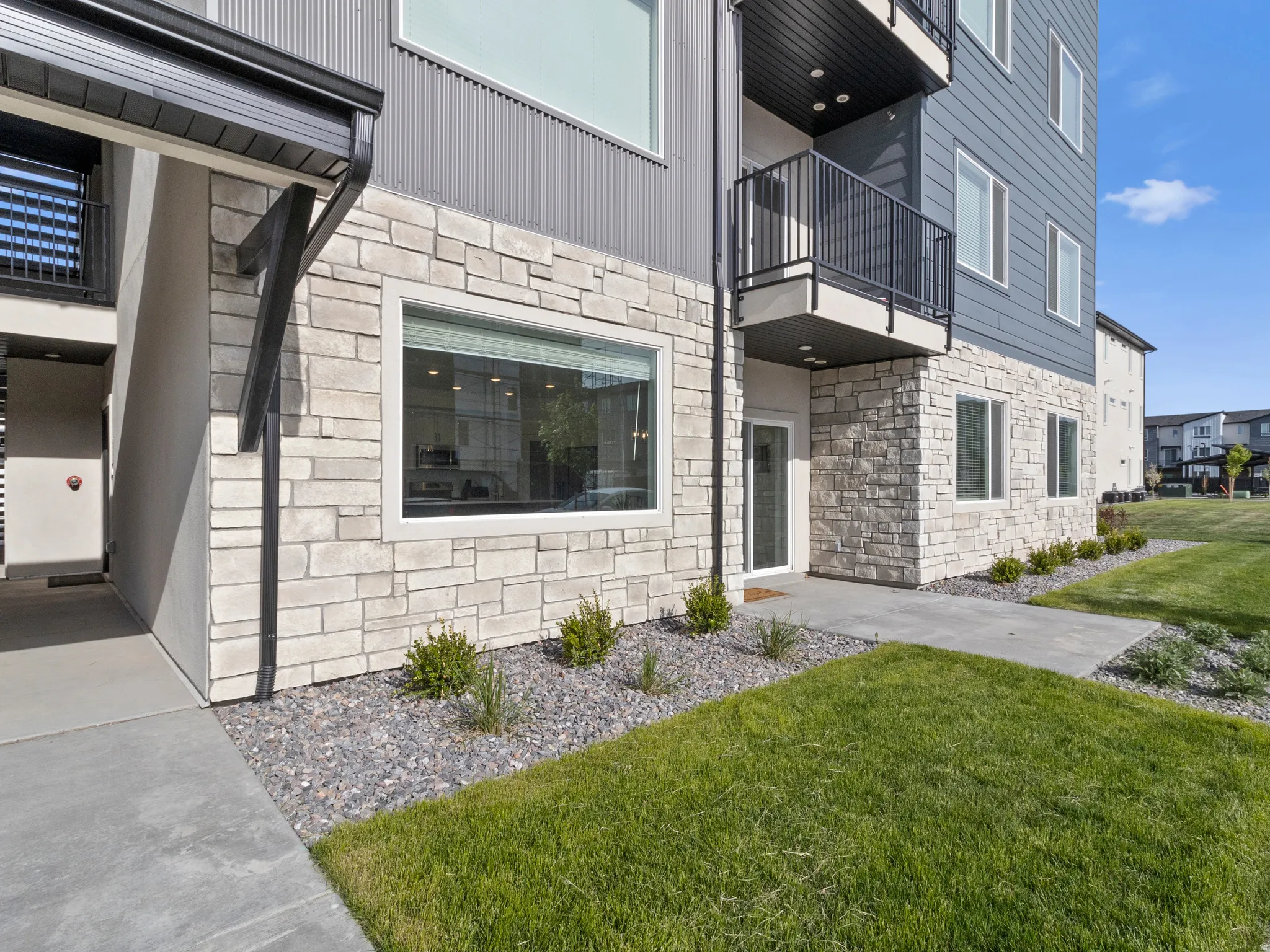 Entrance to property featuring stone siding and a lawn