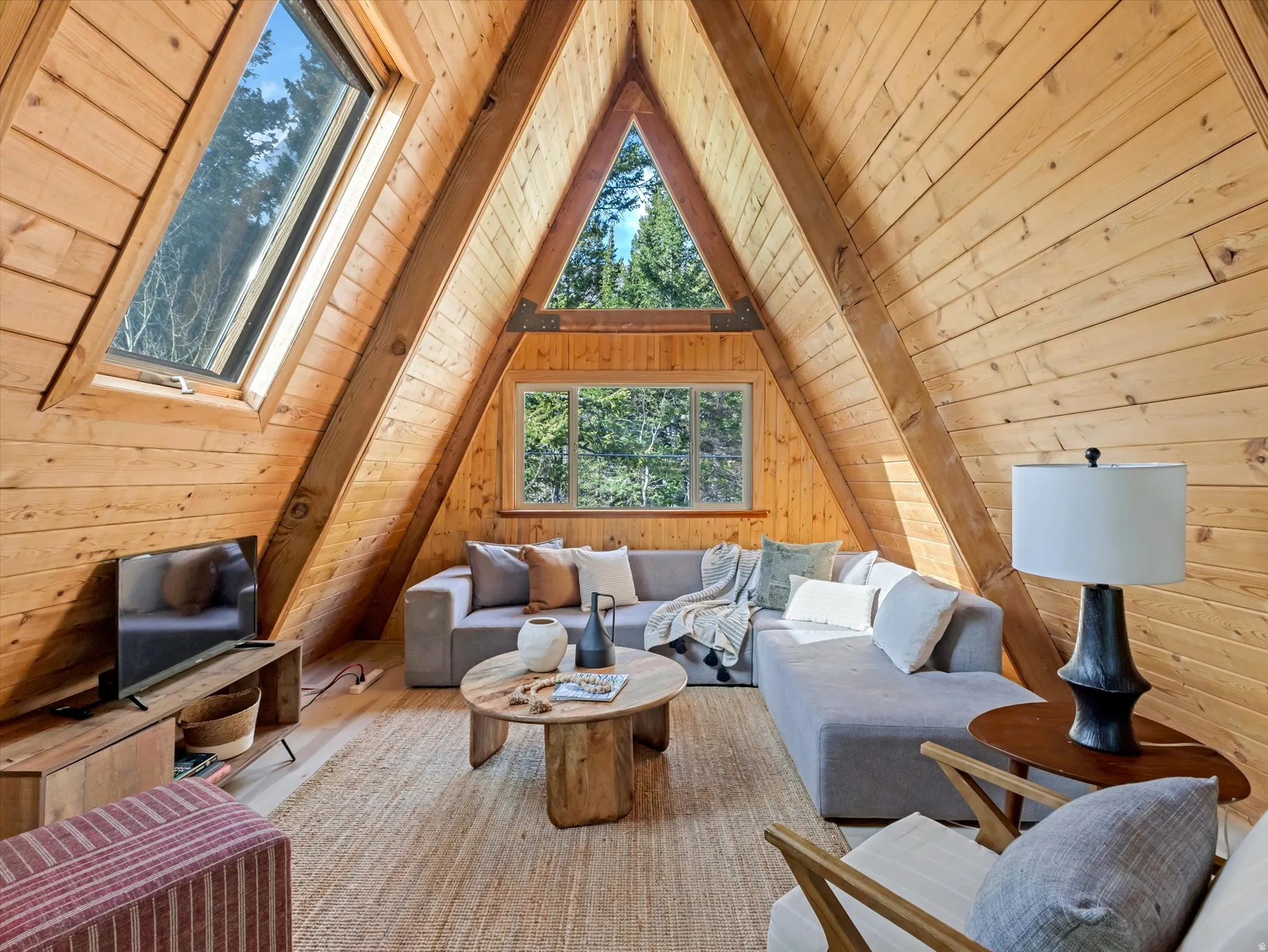 Living room with a wood ceiling with exposed beams and wooden walls