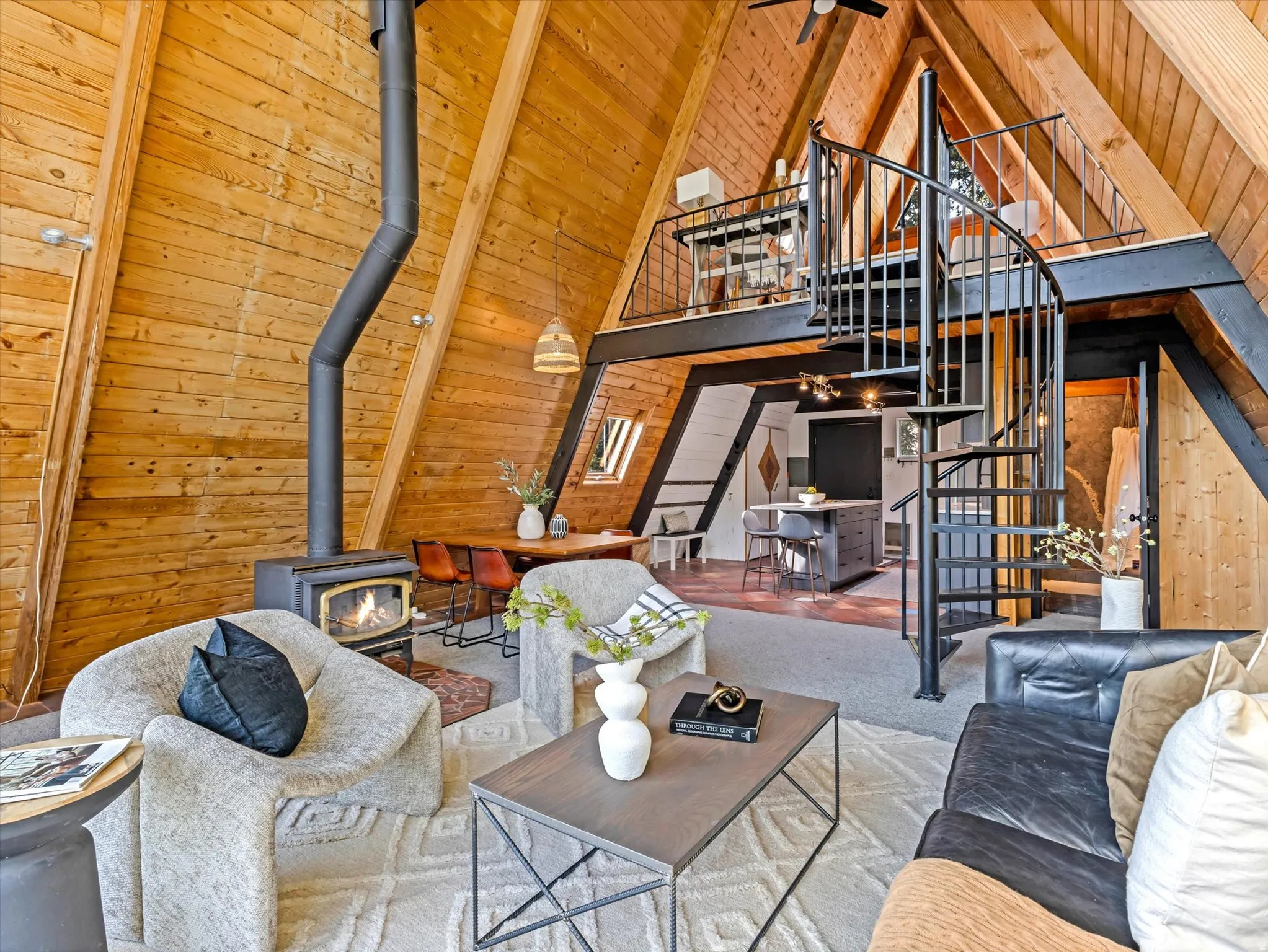 Living area with wooden walls, a wood stove, a high wood beamed ceiling, and carpet floors