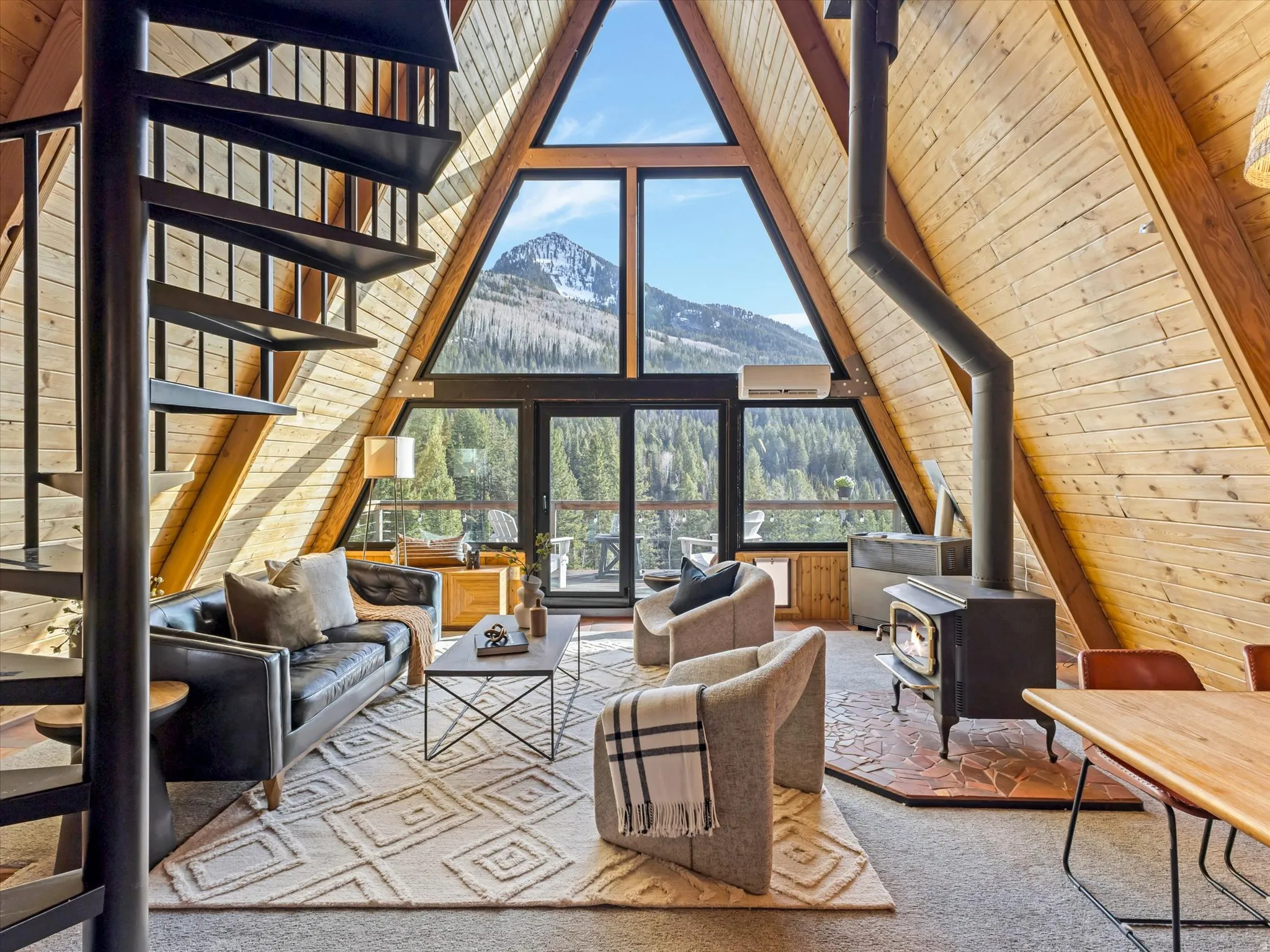 Living area with a high wood beamed ceiling, a wood stove, wooden walls, a mountain view, and carpet flooring
