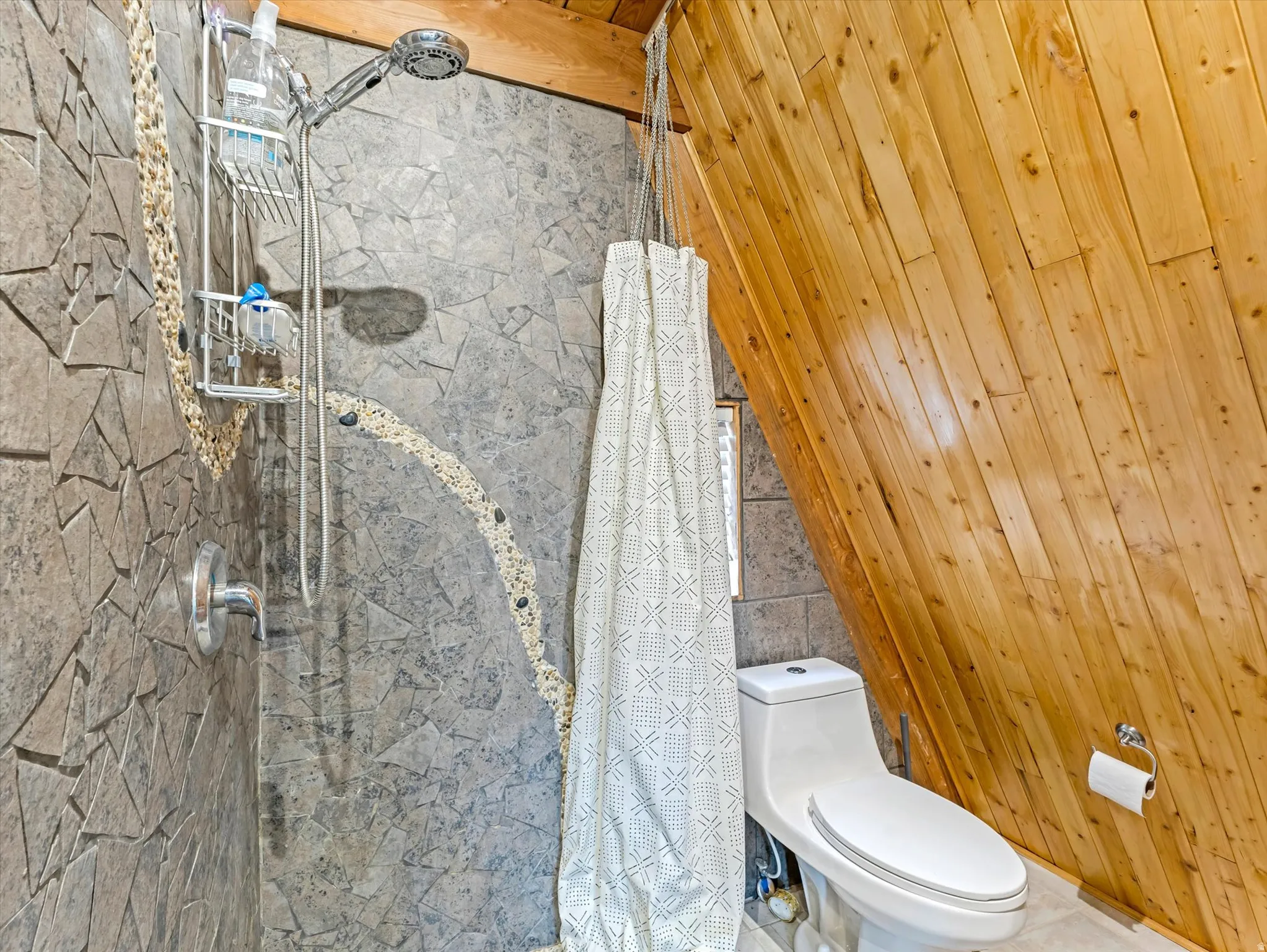 Full bath featuring a stall shower and tile walls