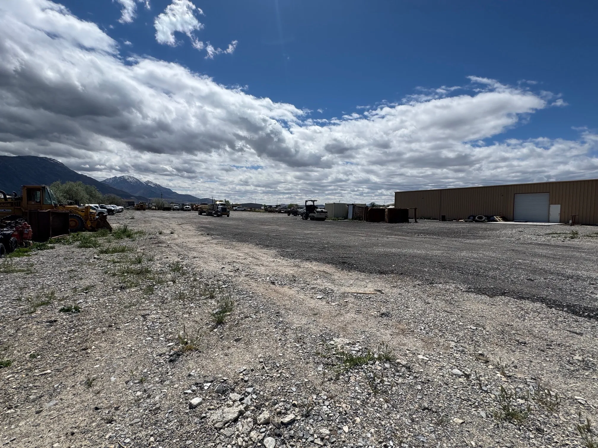 Expansive gravel lot featuring a large commercial building with a roll-up door