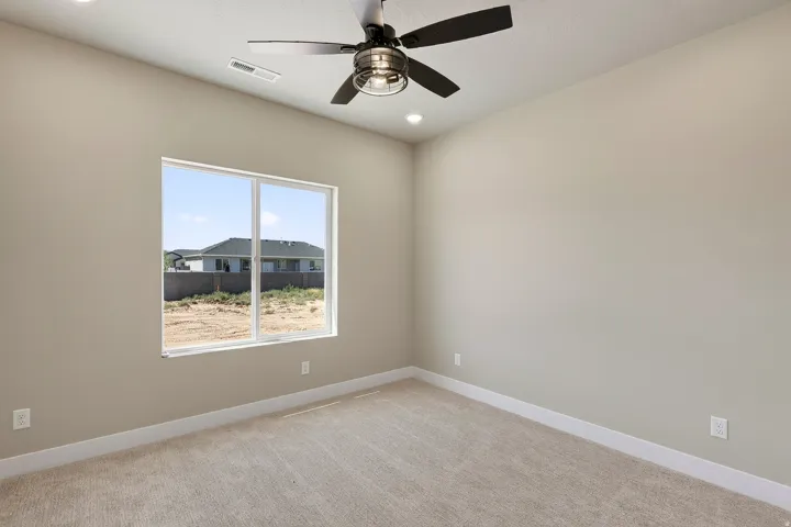 Carpeted room featuring a ceiling fan with integrated lighting, recessed ceiling lights, a large window, and light-toned walls with white baseboards