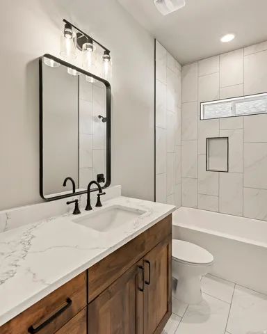 Bathroom vanity featuring a white countertop with integrated sink, dark wood-finish cabinetry, and matte black hardware
