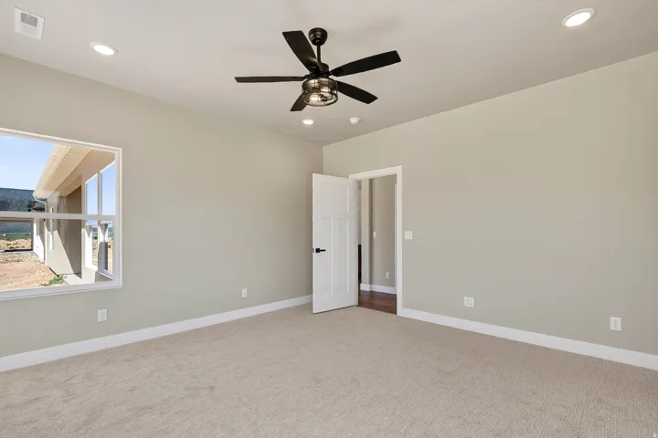 Carpeted room featuring a ceiling fan with integrated lighting, recessed ceiling lights, and light-toned wall paint with white trim