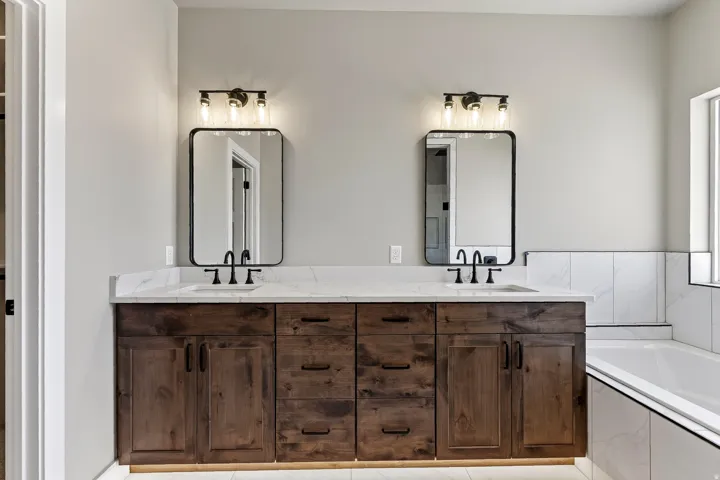 Double vanity featuring wood cabinetry with black hardware, white countertop, and integrated sinks