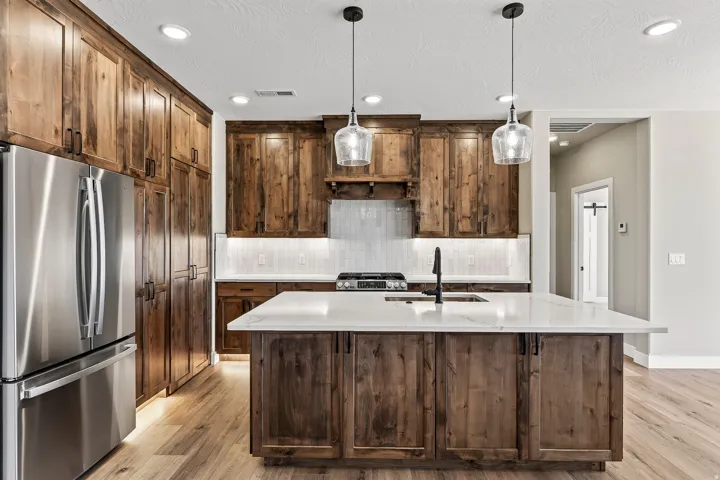 Expansive kitchen featuring wood-finish cabinetry, a large center island with a white countertop, and stainless steel appliances