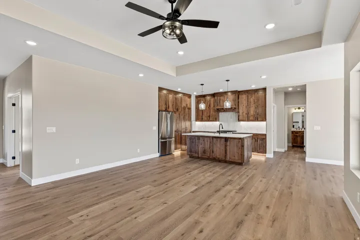 Spacious living area featuring wood-finish flooring, a tray ceiling, and recessed lighting