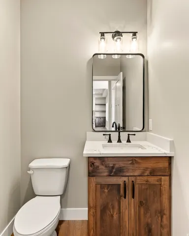 Powder room featuring a wood-finish vanity with a white countertop and a rectangular undermount sink, complemented by a matte black faucet