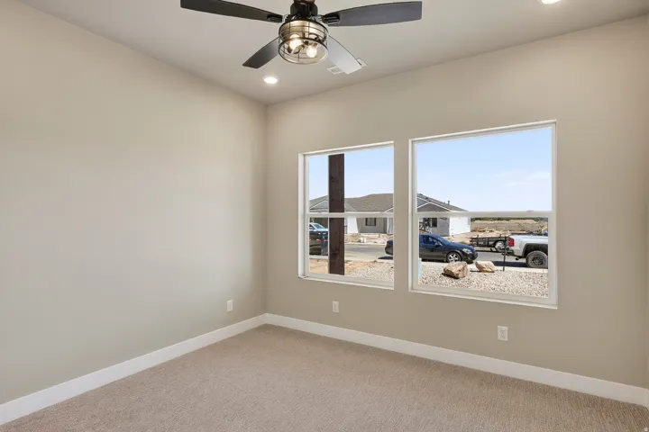Neutral-toned room featuring a ceiling fan with integrated lighting, recessed lighting, and two large windows