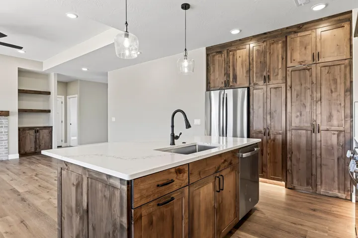 Kitchen island with an undermount sink and matte black faucet, featuring a light-toned countertop and wood-finish cabinetry