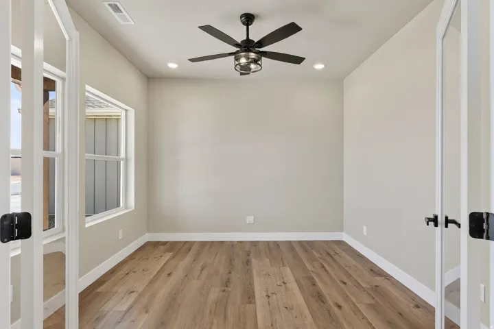 Neutral-toned room featuring a ceiling fan with integrated lighting, recessed lighting, and wood-finish flooring