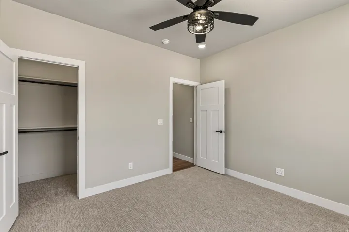 Carpeted room featuring a ceiling fan with integrated lighting, recessed lighting, white baseboards, and a closet with shelving and hanging rods
