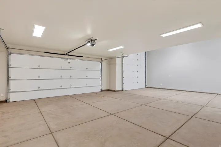 Spacious garage featuring two overhead doors, concrete flooring, and multiple ceiling-mounted light fixtures