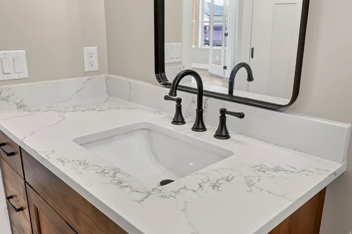 Vanity featuring a white countertop with gray veining, an undermount sink, and a matte black faucet set