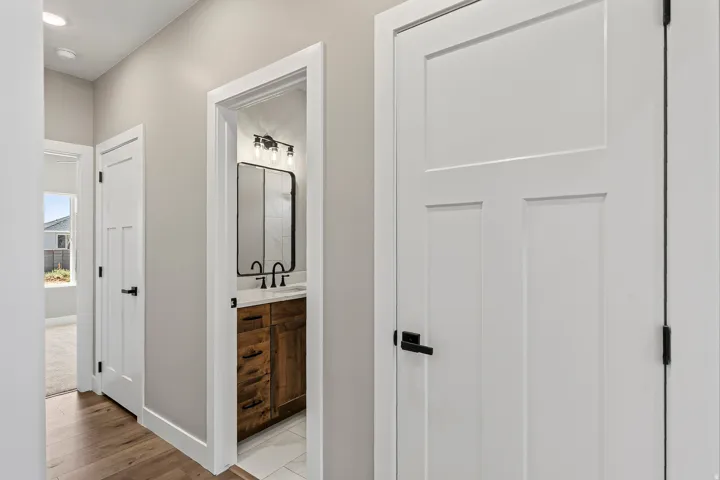 Hallway featuring wood-finish flooring, white paneled doors with matte black hardware, and recessed lighting