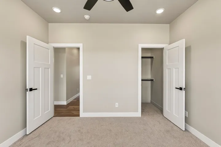 Neutral-toned room featuring carpet flooring, recessed lighting, a ceiling fan, and white trim