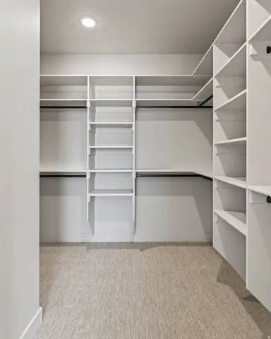 Walk-in closet featuring extensive built-in shelving, multiple hanging rods, recessed lighting, and textured carpet flooring