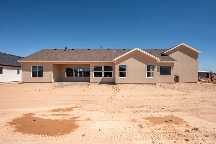 Stucco exterior with a brown shingle roof and multiple windows
