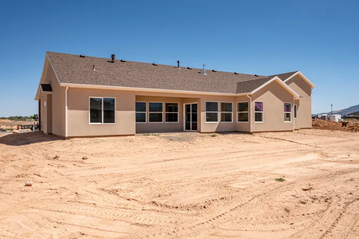 Rear exterior featuring stucco finish, a covered patio, and multiple large windows