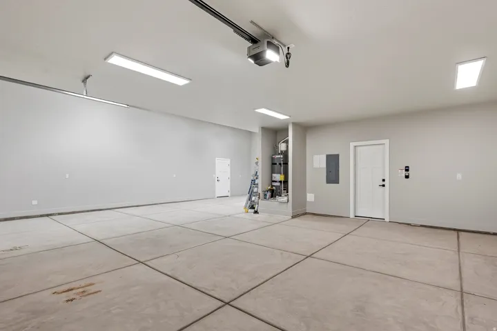 Spacious garage featuring a concrete floor, multiple ceiling-mounted linear light fixtures, and painted walls