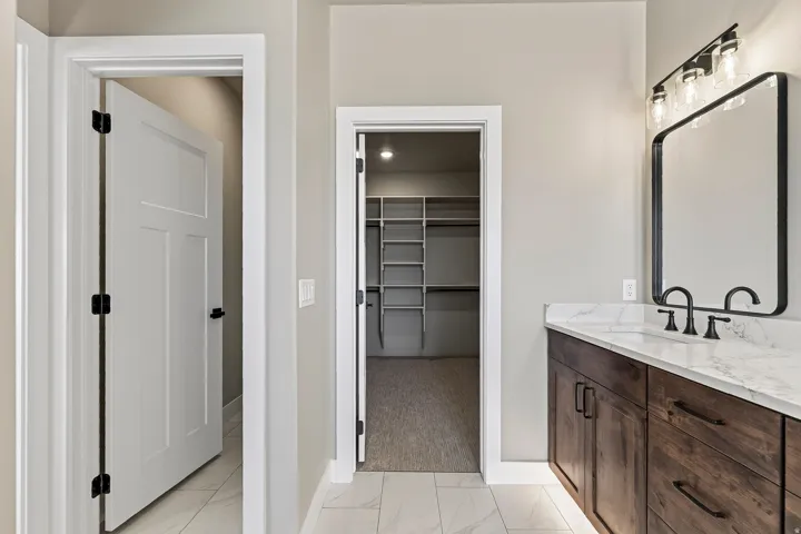 Bathroom vanity featuring dark wood-finish cabinetry, a white countertop, and a rectangular black-framed mirror