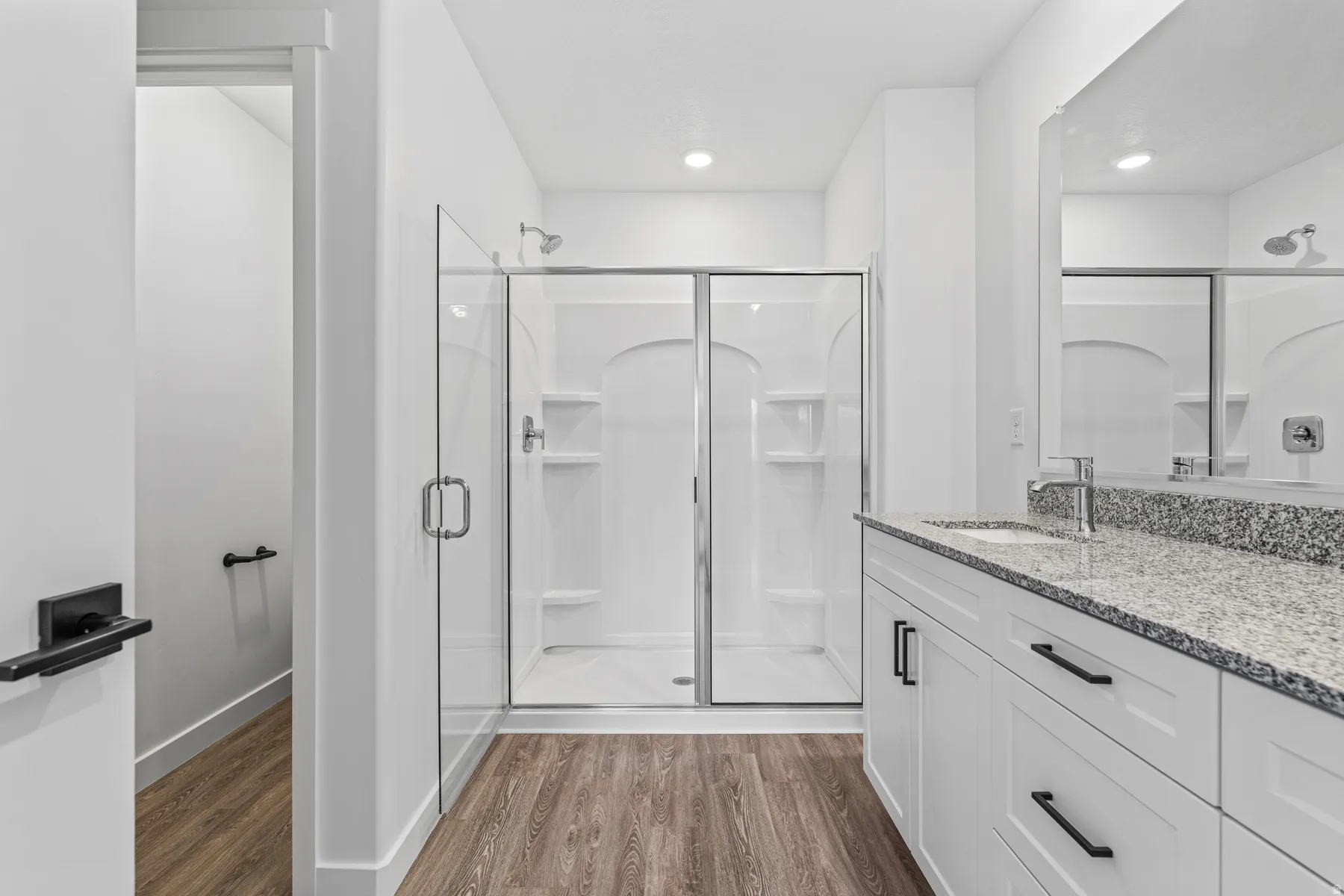 Modern bathroom featuring a double vanity with stone countertop, undermount sink, and chrome faucet