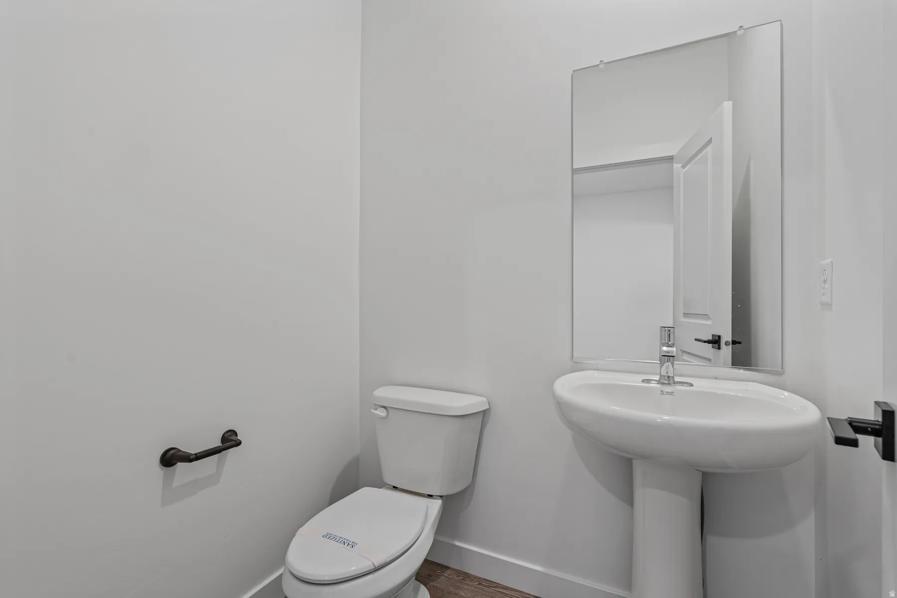 Contemporary powder room featuring a pedestal sink, rectangular mirror, and dark bronze fixtures
