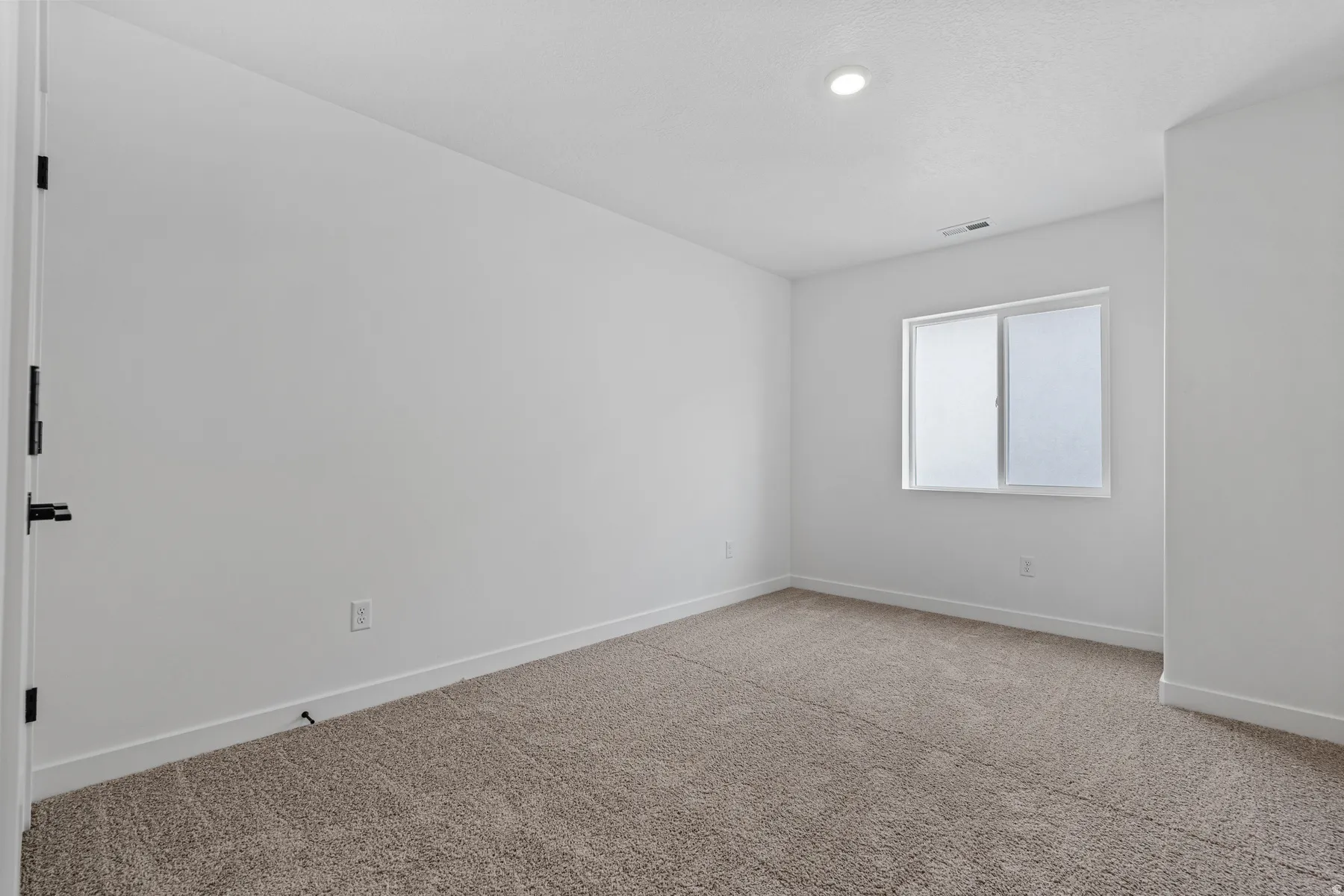 Spacious room featuring neutral carpeting, a large window, white walls, recessed lighting, and white baseboards