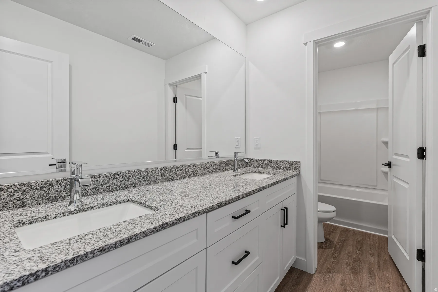 Double vanity featuring a granite countertop, undermount sinks, and chrome faucets