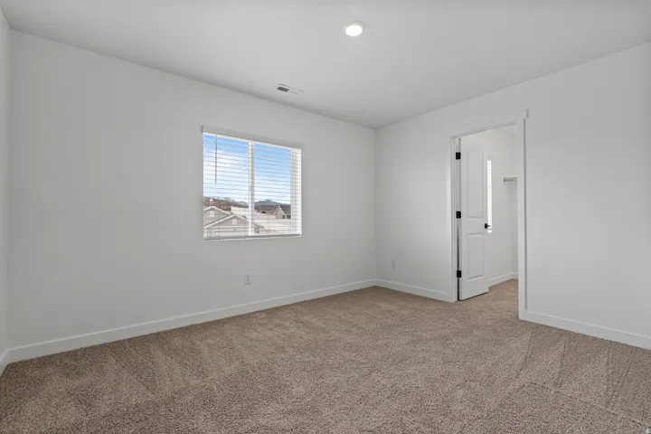 Carpeted room with white walls, a single window featuring horizontal blinds, and a recessed ceiling light
