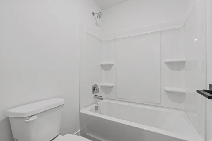 White fiberglass tub/shower combination with integrated shelving
