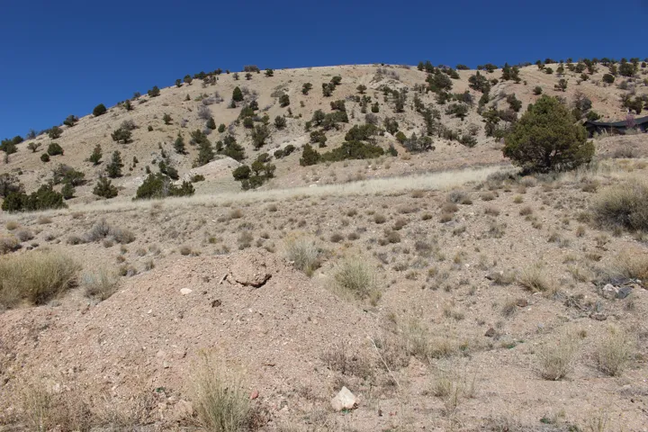 Hillside terrain with sparse vegetation and clear blue sky