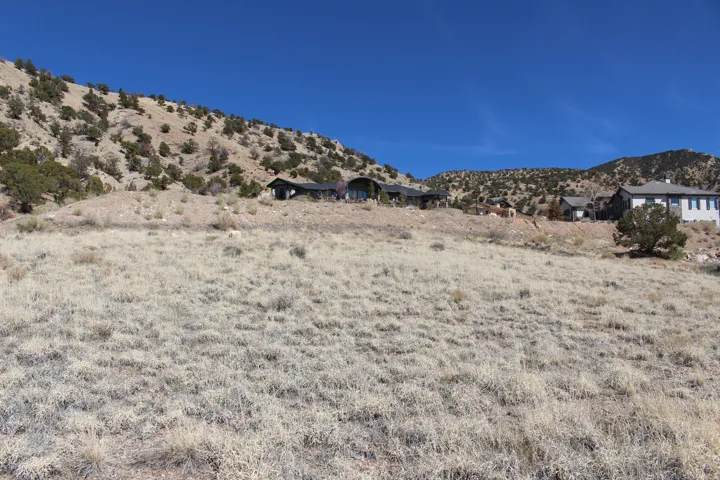 Expansive natural landscape featuring a sloped terrain and distant structures against a clear blue sky