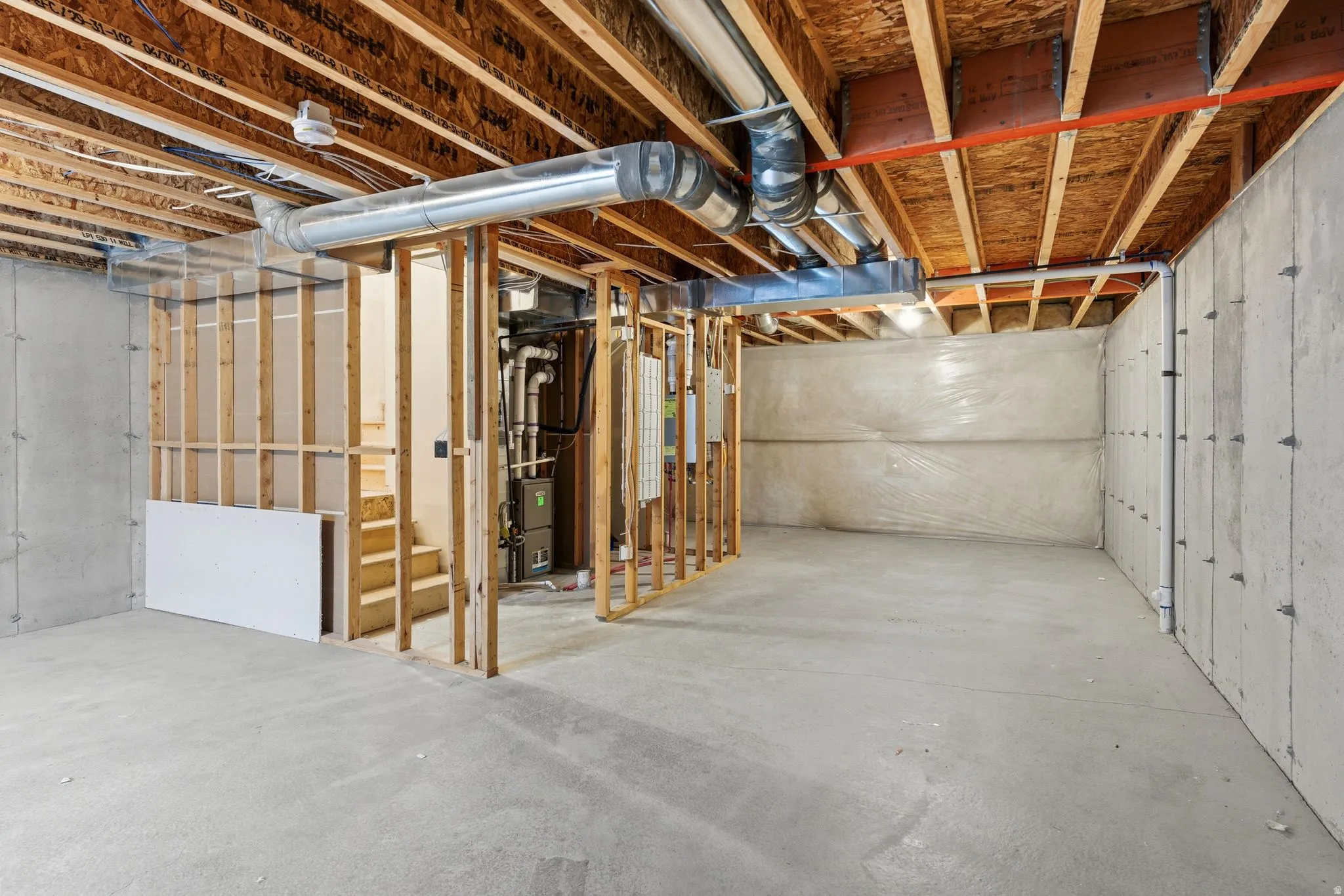 Unfinished basement featuring concrete flooring, exposed wood joists, and visible HVAC ductwork