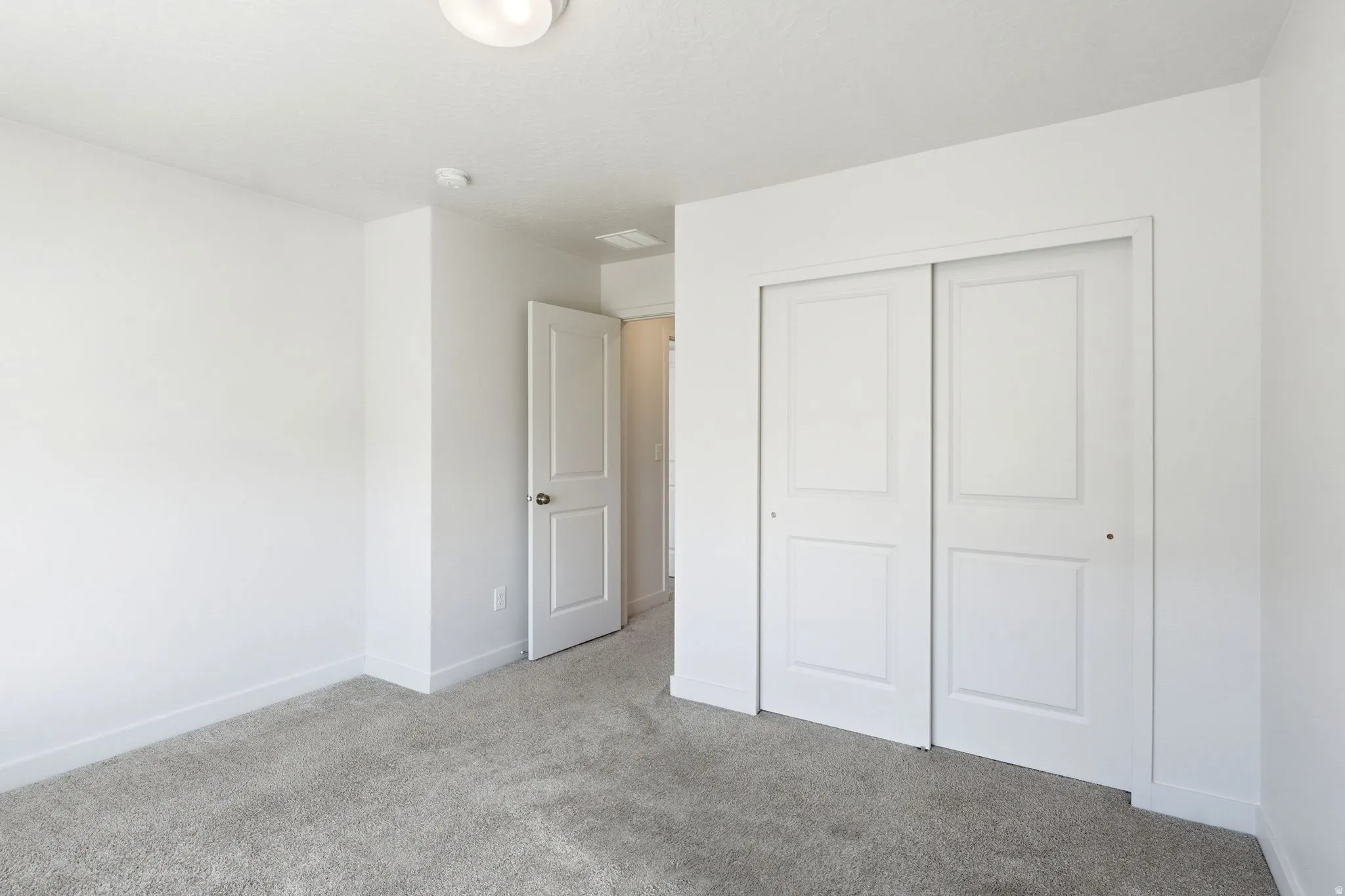 Carpeted room featuring white walls, a white ceiling, recessed lighting, and a bi-fold closet door